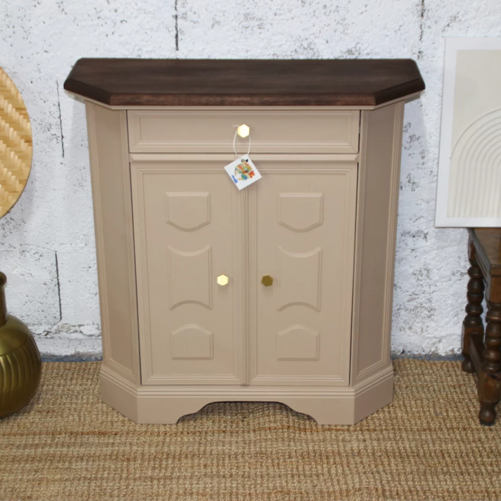 Meuble d'appoint – Armoire élégante avec une base beige et un plateau en bois foncé, dotée de deux portes et d'un tiroir, placée devant un fond texturé.