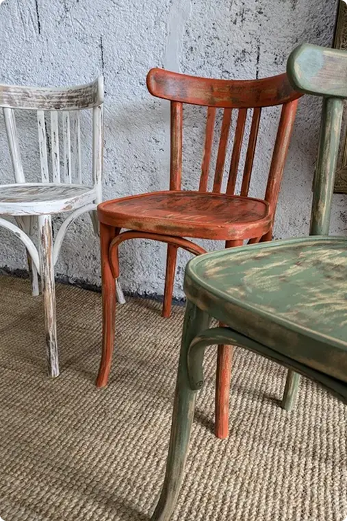 Trois chaises colorées en bois variés, chacune affichant un design unique et une esthétique distinctive.